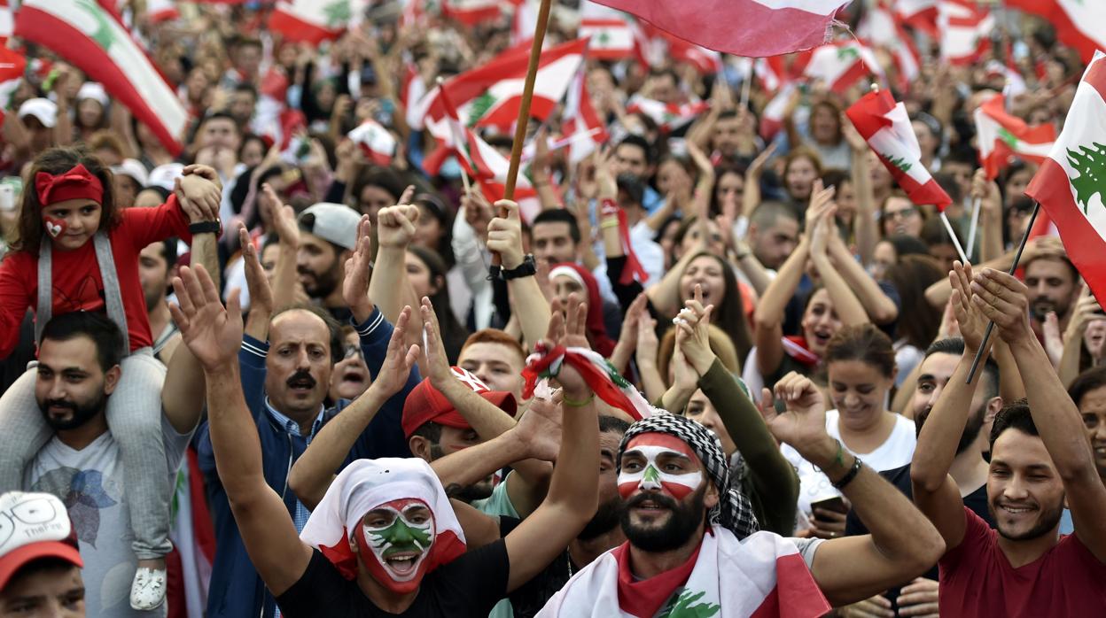 Los manifestantes llevan banderas libanesas y gritan consignas antigubernamentales en el décimo día de protesta en el centro de Beirut