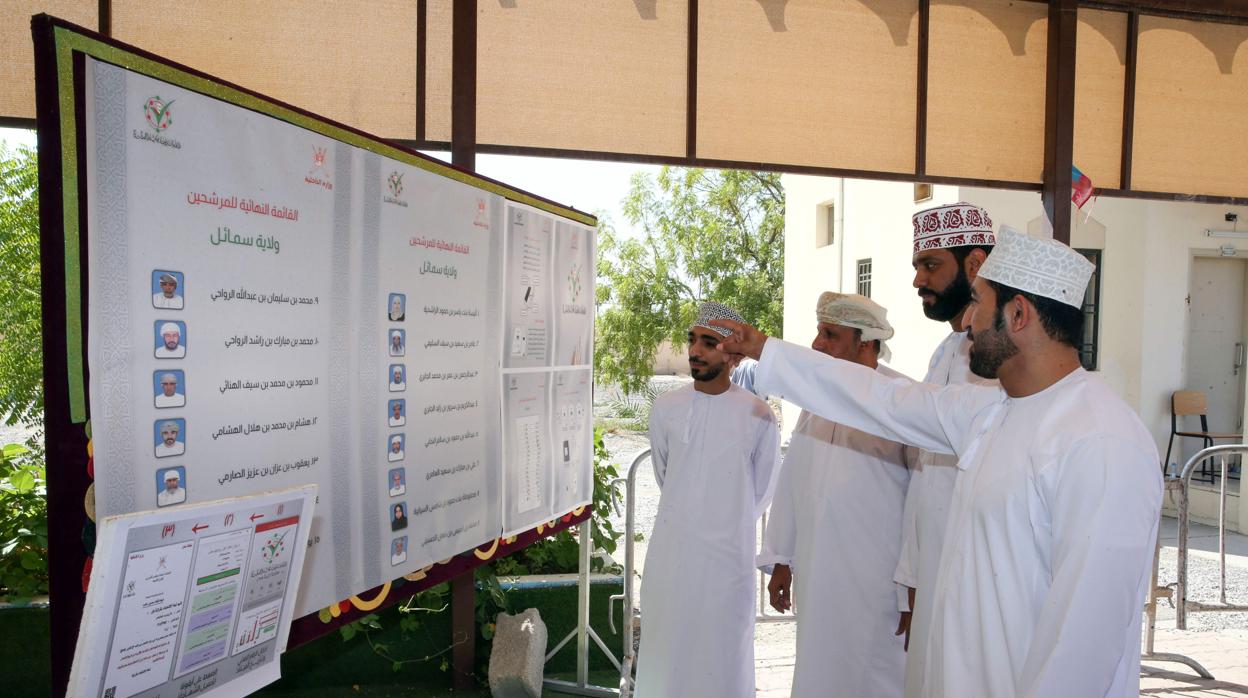 Los hombres omaníes miran las listas de candidatos para las elecciones del consejo consultivo