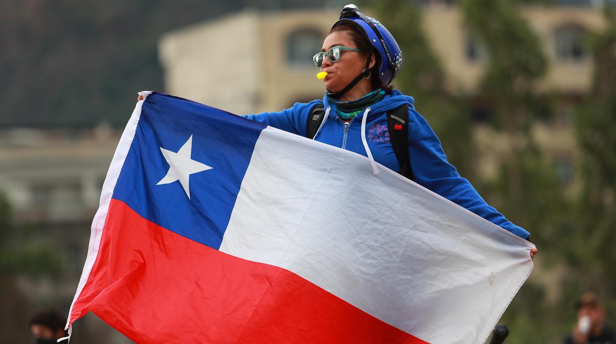 Una manifestante protesta contra el Gobierno con una bandera nacional en Santiago de Chile