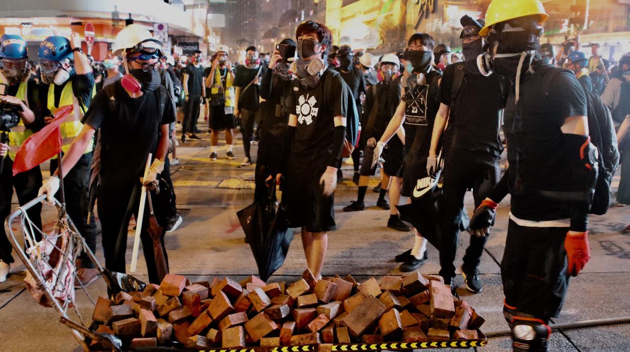 Jóvenes radicales cargan adoquines para enfrentarse a la Policía en el distrito comercial de Causeway Bay