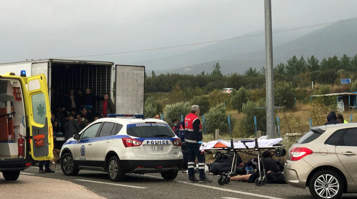Los migrantes son vistos dentro de un camión refrigerado mientras otros yacen en el camino, después de que un control policial en una autopista cerca de Xanthi