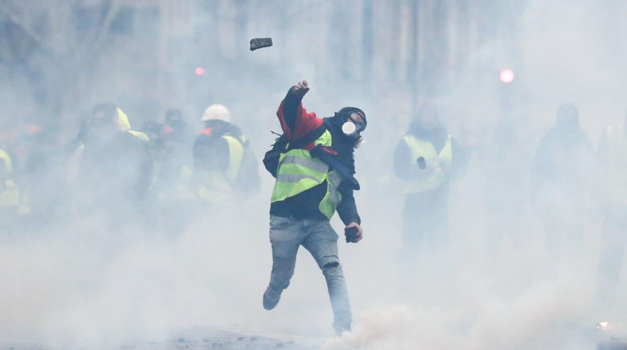 Un chaleco amarillo lanza un adoquín a la Policía durante las protestas de los chalecos amarillos