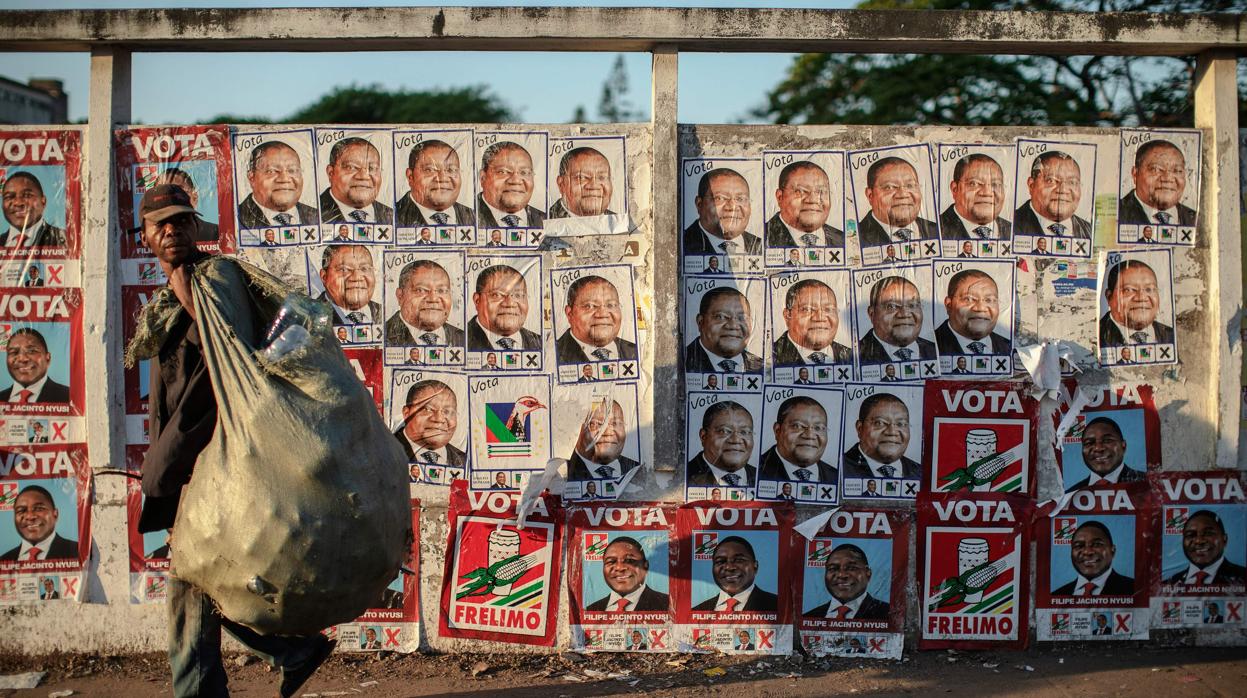 Un hombre camina por una pared repleta de afiches de los candidatos a las elecciones