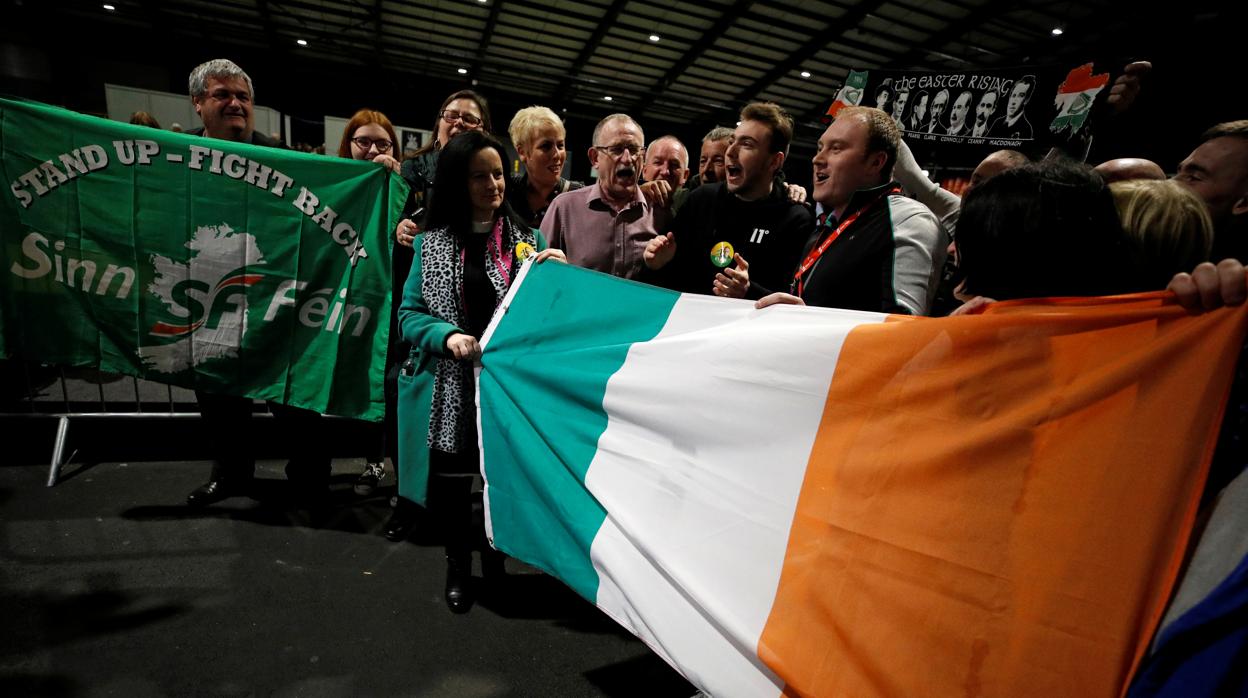 Simpatizantes del Sinn Fein sostienen una bandera irlandesa tras votar este domingo