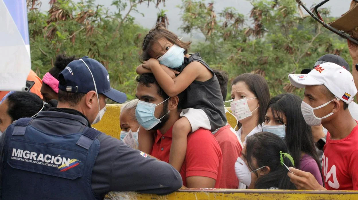Venezolanos con mascarillas hacen cola para pasar por los puentes fronterizos hacia Colombia
