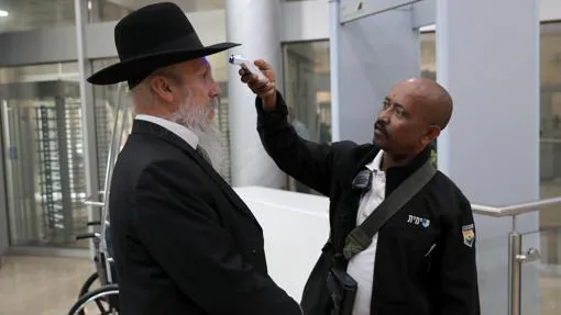 Un policía israelí toma la temperatura a un judío ortodoxo