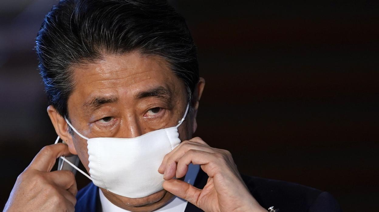 El primer ministro japonés, Shinzo Abe, se quita la mascarilla antes de participar en una rueda de prensa