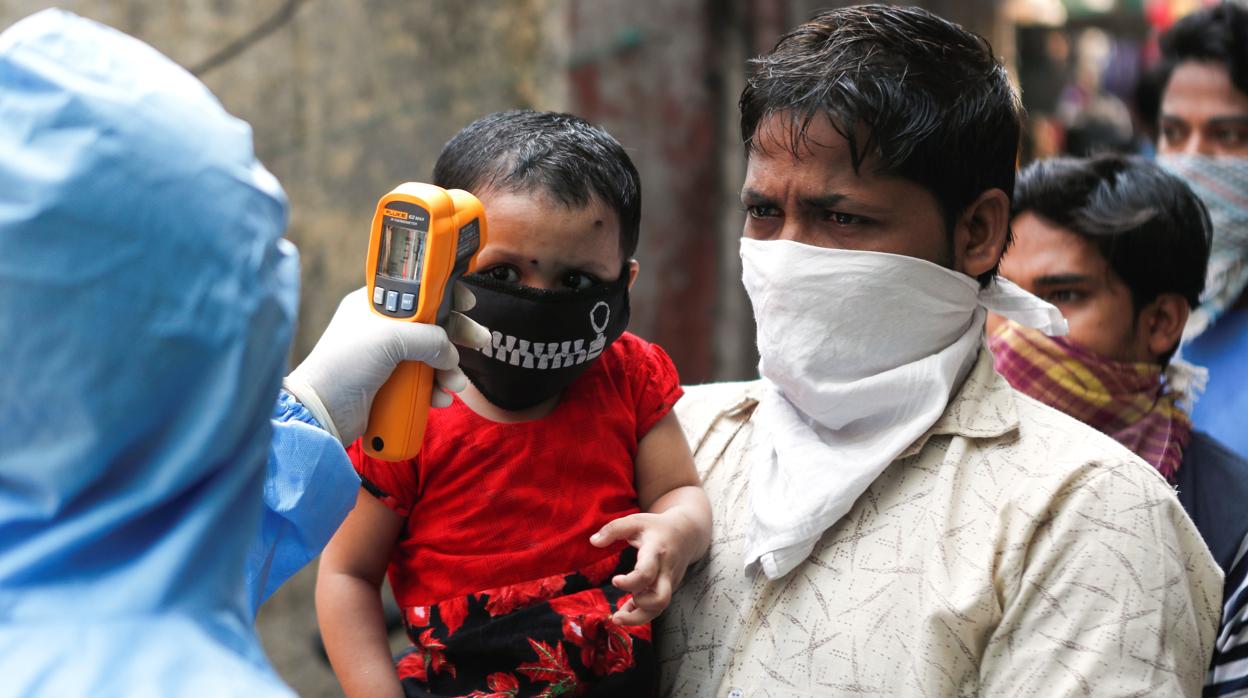 Personal sanitario toma la temperatura en Dharavi, en Bombay, uno de los mayores barrios pobres de Asia