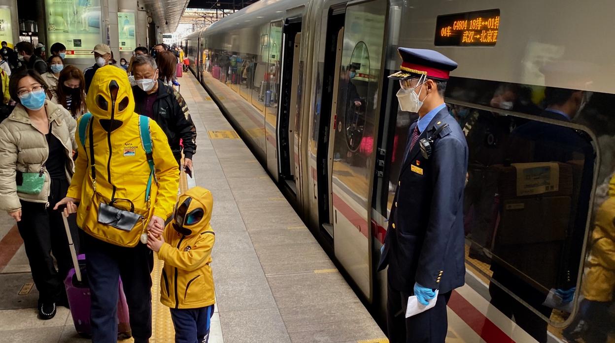 Ataviados con una especie de traje «zentai» japonés para protegerse del coronavirus, una madre y su hijo llegan a la Estación del Oeste de Pekín