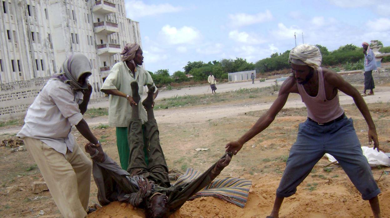 Foto de archivo de un grupo de milicianos de Al Shabab enterrando el cadáver de un soldado del gobierno en una calle de Somalia