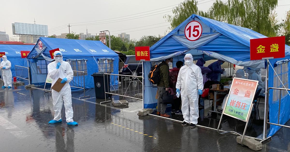 Pertrechados con trajes de protección especial, funcionarios de Pekín registran y toman la temperatura a los viajeros procedentes de Wuhan, que deben guardar una cuarentena de dos semanas