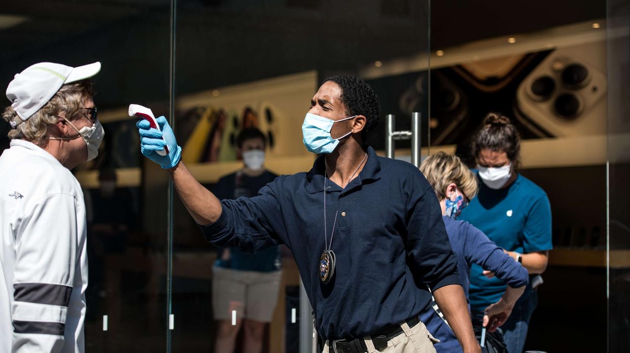 Un guardia de seguridad toma la temperatura a un cliente en la reapertura de una tienda de Apple en Charleston (Carolina del Sur)