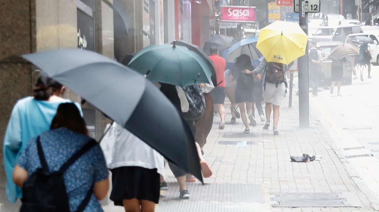 Un grupo de hongkoneses se protegen del gas lacrimógeno con paraguas