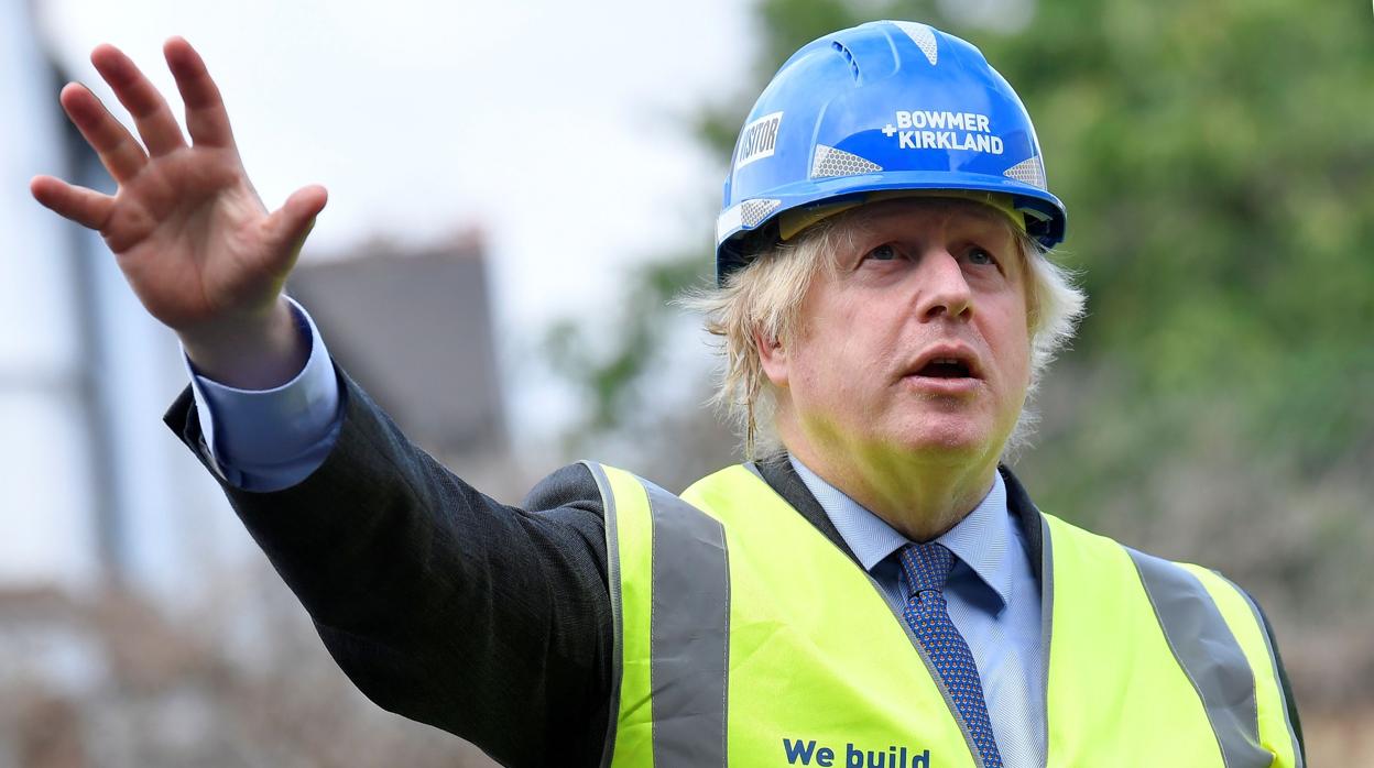 El primer ministro británico Boris Johnson hace señas con la mano en una construcción