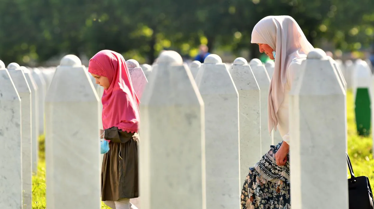 Una mujer, que sobrevivió al genocidio de 1995, y su nieta visitan las tumbas de sus familiares