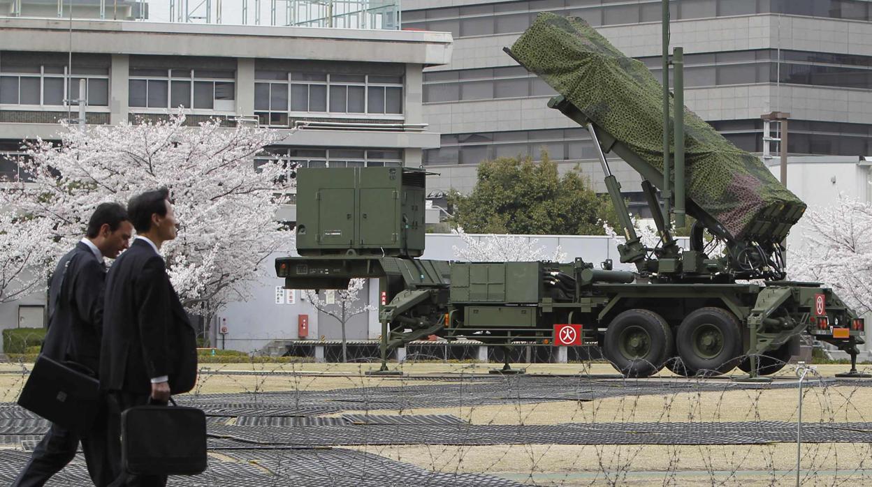 Unos hombres caminan junto a unos misiles Patriot tiera-aire en Tokio