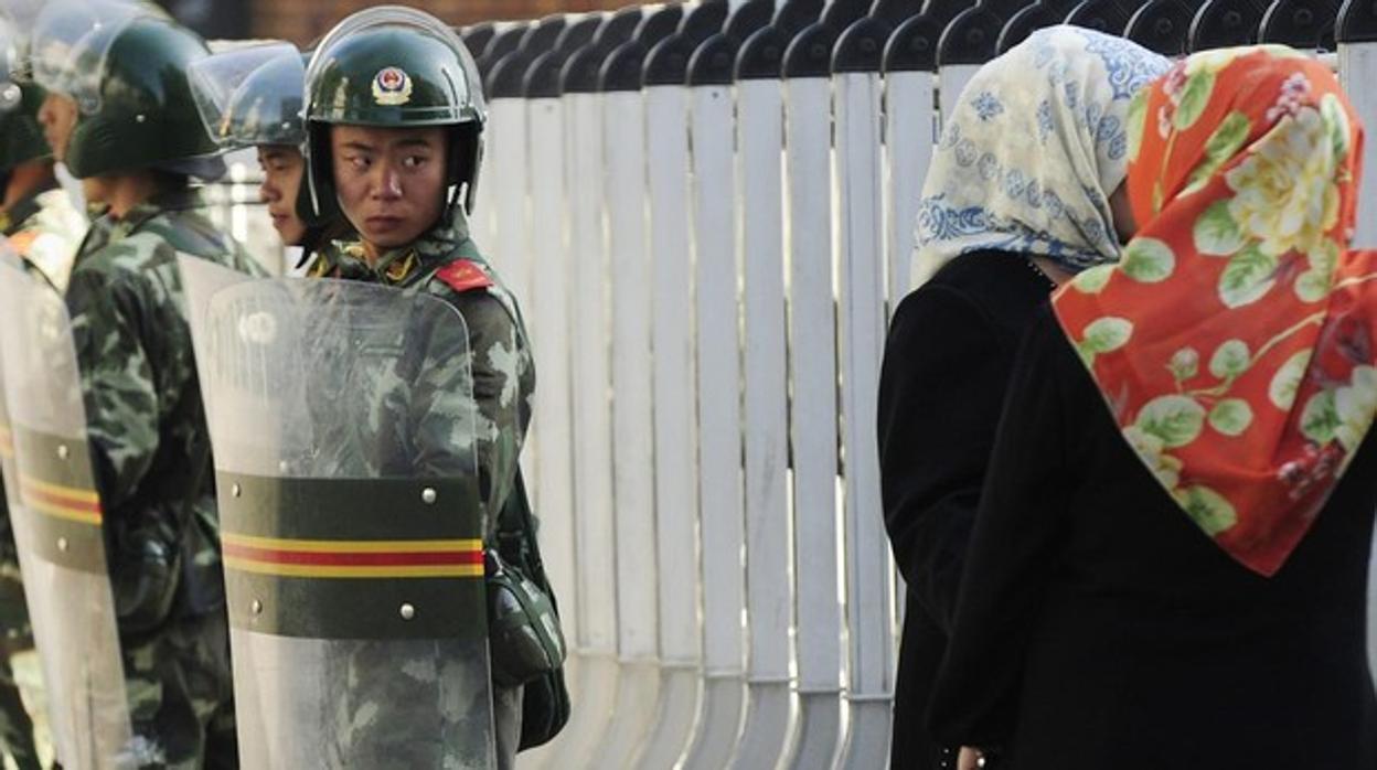 Un policía observa a una mujer uigur en Umqir, la capital de la región de Xinjiang