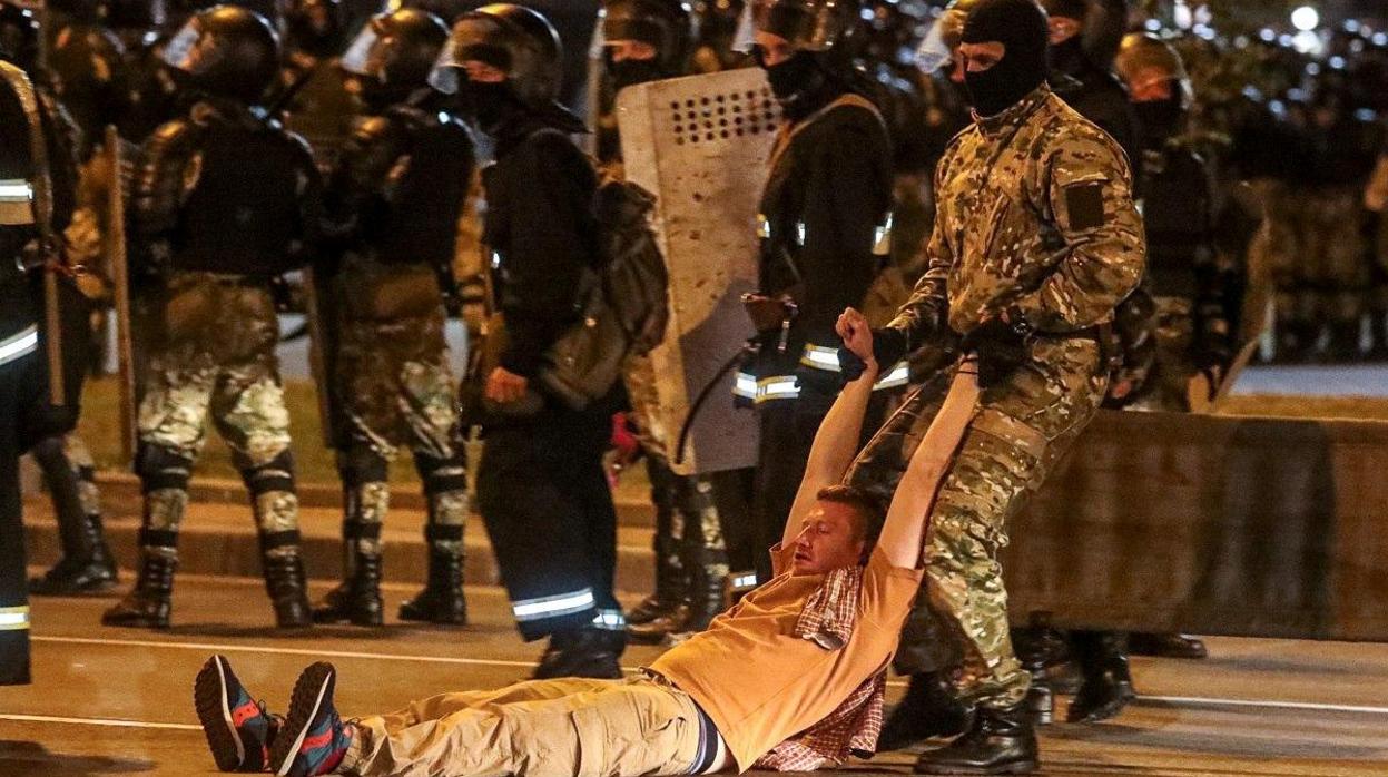 Un miembro de las fuerzas de seguridad arrastra a un hombre durante los enfrentamientos con seguidores de la oposición tras las elecciones presidenciales de Bielorrusia en Minsk