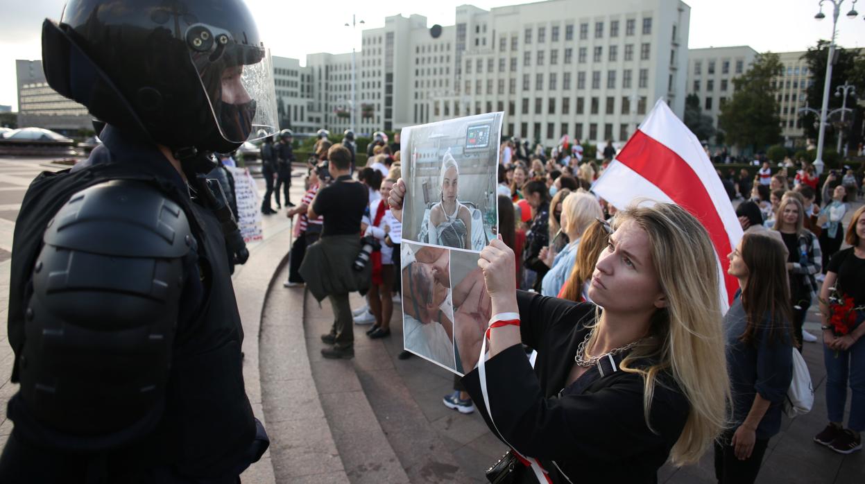 Una mujer muestra a un miembro de las fuerzas de seguridad bieolurrusas la foto de una herida en las protestas