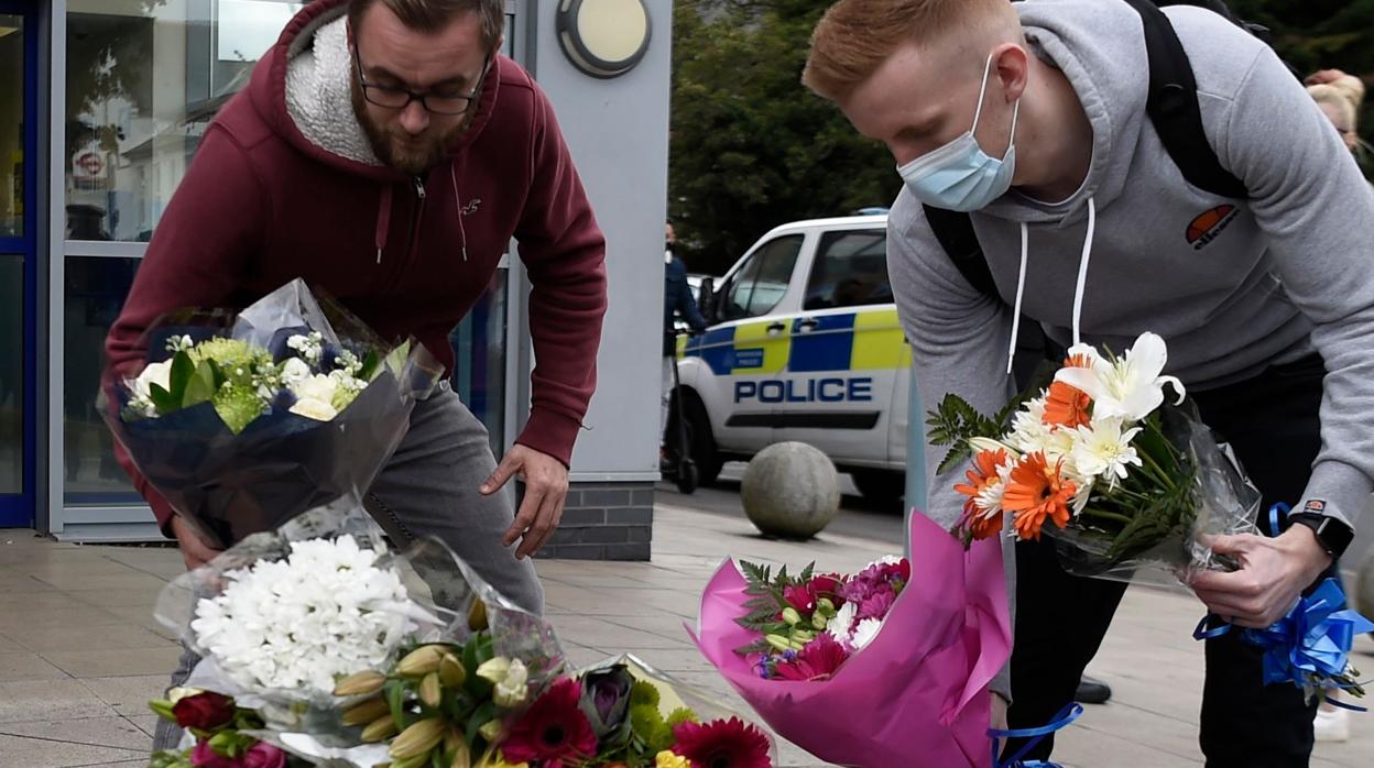 Dos personas depositan flores cerca de la comisaría donde el agente murió