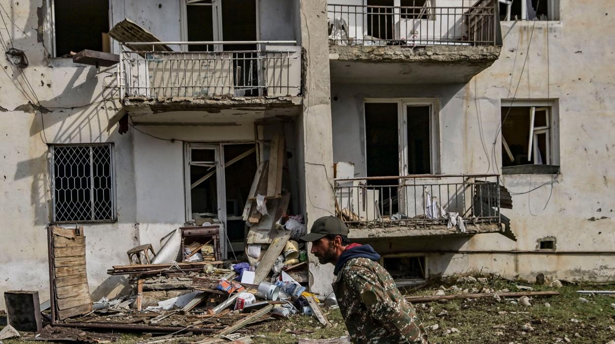 Un hombre camina frente a un edificio destruido en Nagorno Karabaj