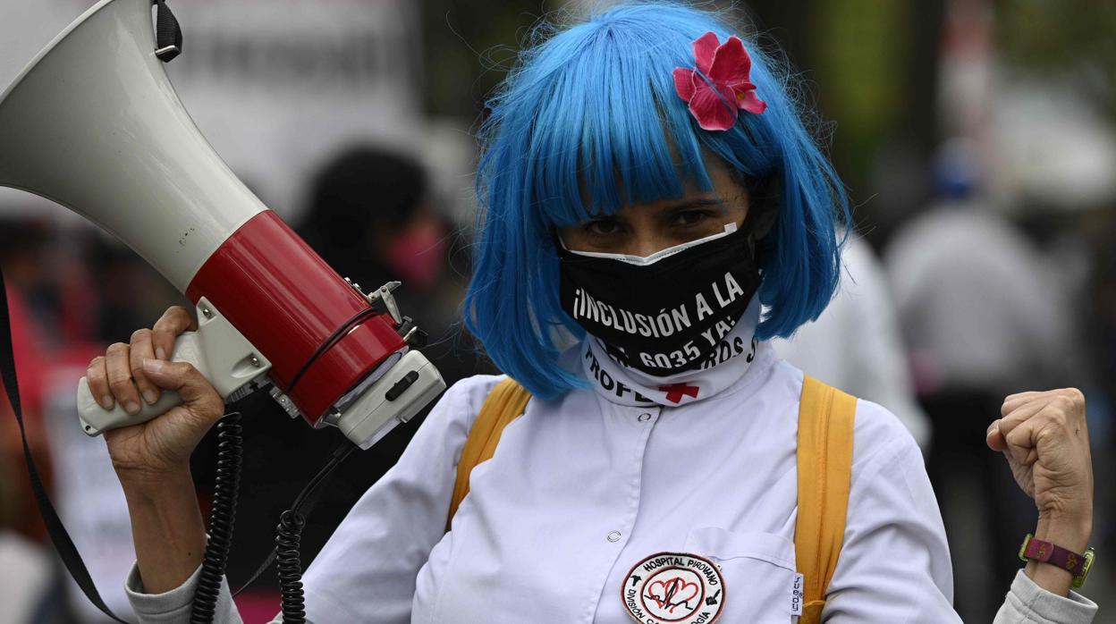 Una mujer participa en una protesta en Buenos Aires, protegiéndose del coronavirus con una mascarilla