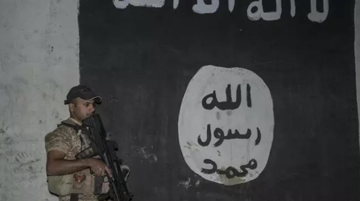 Un soldado iraquí junto a una bandera de Estado Islámico pintada en una pared en Mosul