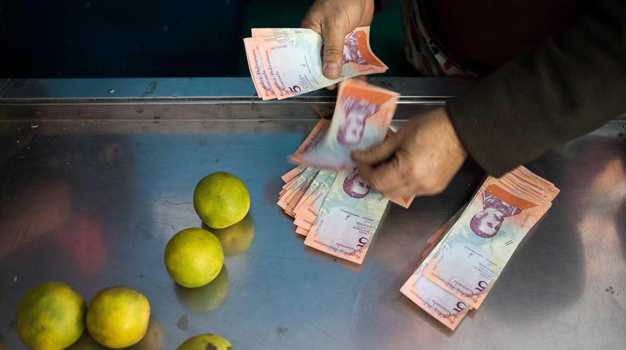Una persona cuenta billetes de bolívar en un mercado de Caracas