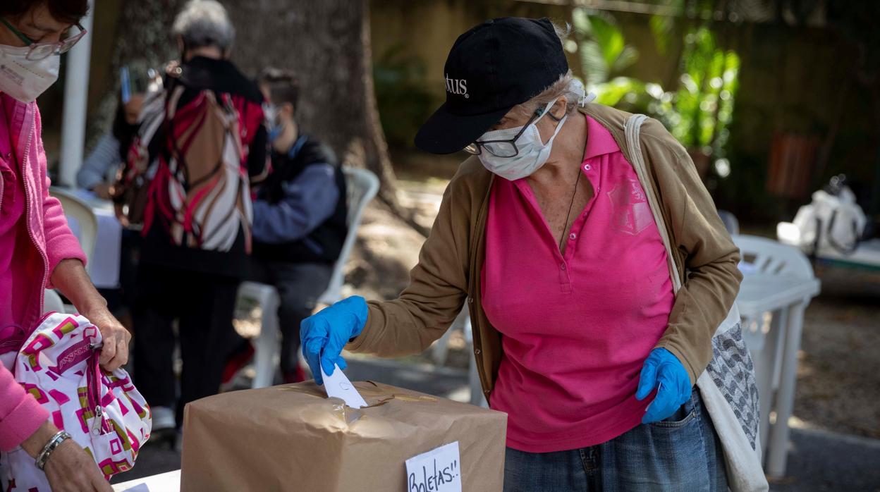 Una mujer depositai su voto en la consulta popular, en Caracas