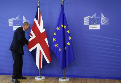 Un empleado de la Unión Europea adereza las banderas británica y europea antes de una reunión entre David Cameron y Jean-Claude Juncker