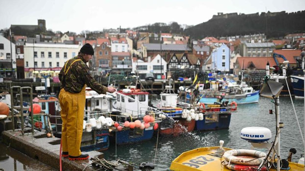 Un pescador limpia su barco en el puerto inglés de Scarborough