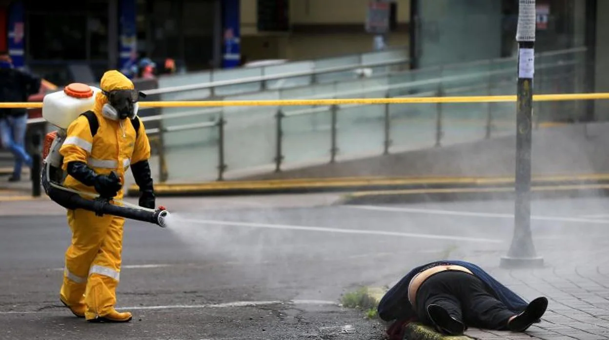 Policía con trajes especiales y personal sanitario asisten este miércoles a una persona que yace en el piso, tras desplomarse y donde criminalística de la policía realizo las pruebas de COVID-19 y determino que falleció por otras causas,en una calle de Quito (Ecuador)