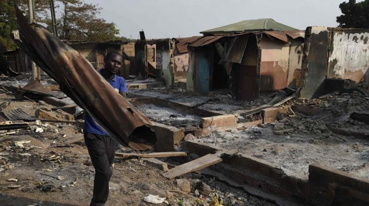 Un hombre lleva una plancha de hierro de una tienda incendida en unos enfrentamientos étnicos en Nigeria