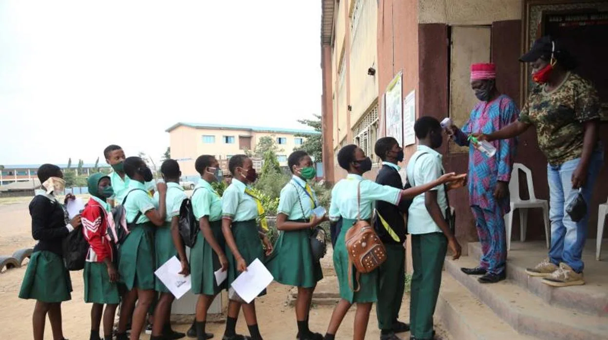 Varios estudiantes esperan para que les tomen la temperatura antes de entrar en una escuela de Nigeria