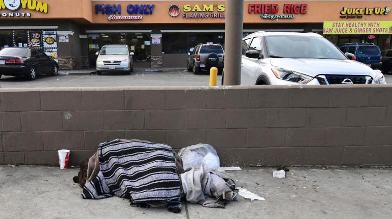 Una persona sin hogar duerme en la acera de una calle de Los Ángeles