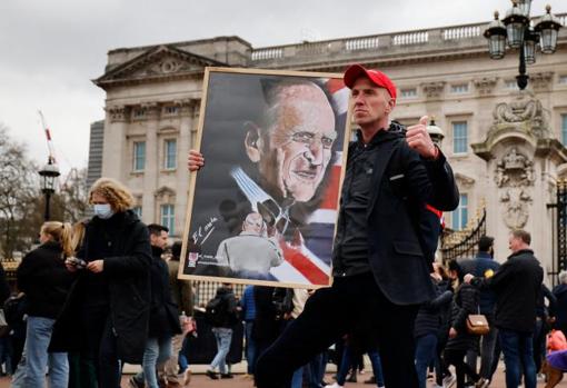 Un ciudadano posa con un retrato de Felipe de Edimburgo frente al Palacio de Buckingham