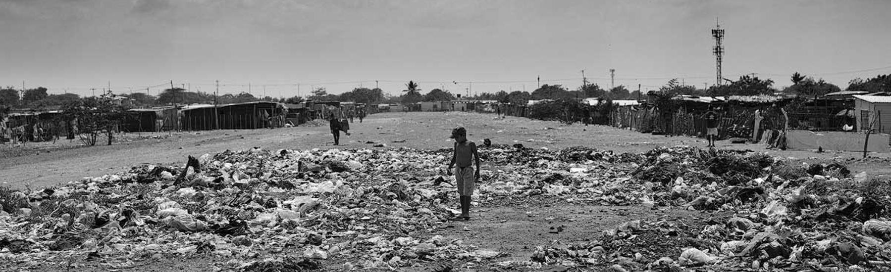 Un menor recoge plástico entre la basura acumulada en la pista de aterrizaje del antiguo aeropuerto de Maicao hoy reconvertido en un asentamiento ilegal de inmigrantes venezolanos