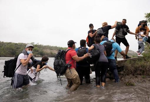 Los inmigrantes se ayudan para alcanzar la orilla estadounidense del río Grande