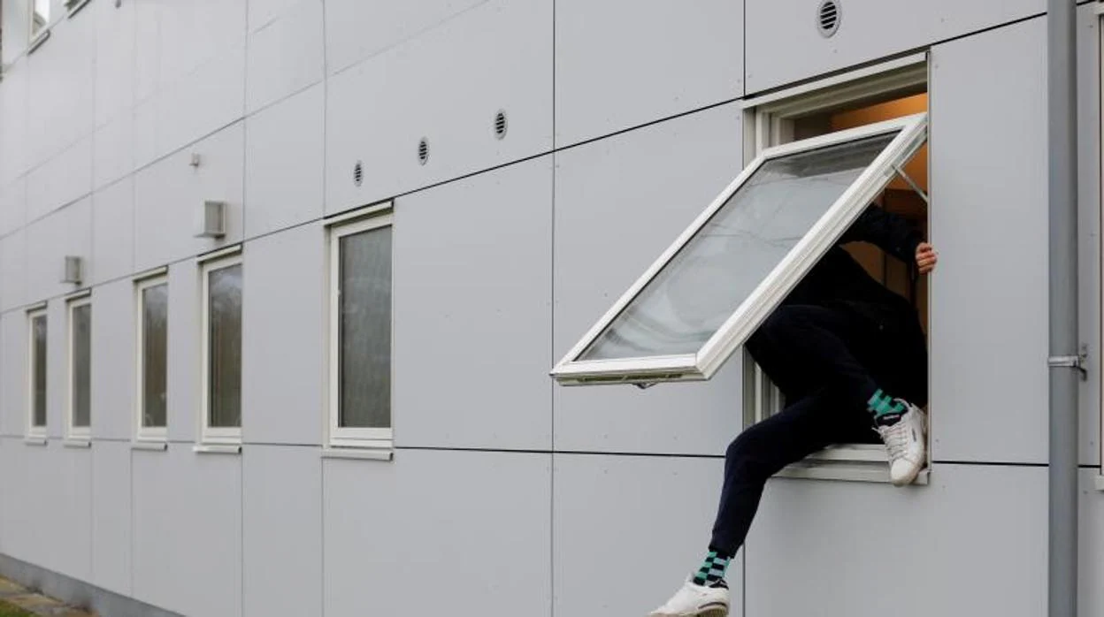 Un residente, encaramado a una ventana de un centro para solicitantes de asilo rechazados en Dinamarca