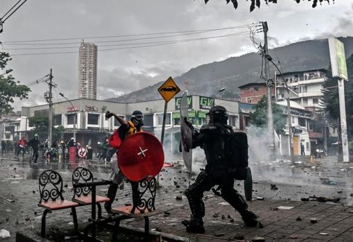 Un manifestante se enfrenta a un policía durante una protesta en Medellín