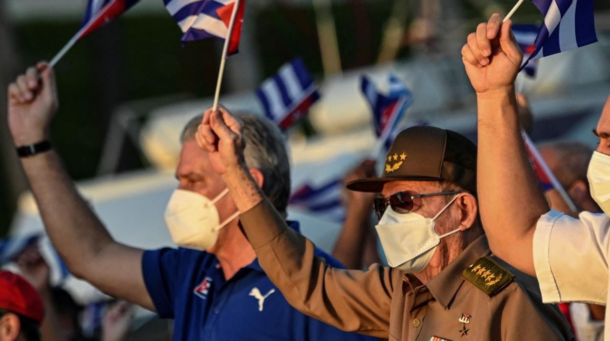 El presidente cubano Miguel Díaz-Canel y Raúl Castro ondean banderas durante un acto