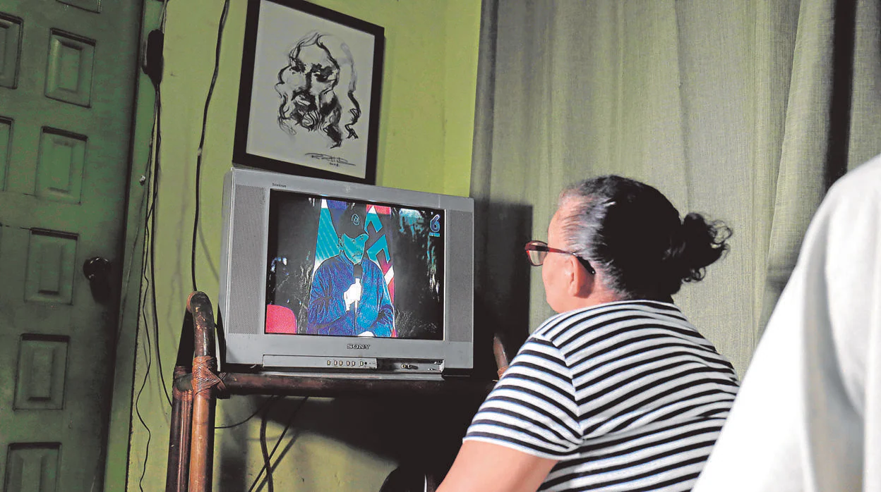 Una nicaragüense escucha la intervención de Ortega en televisión