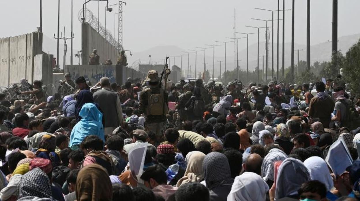 Afganos se reúnen al borde de la carretera cerca de la parte militar del aeropuerto en Kabul