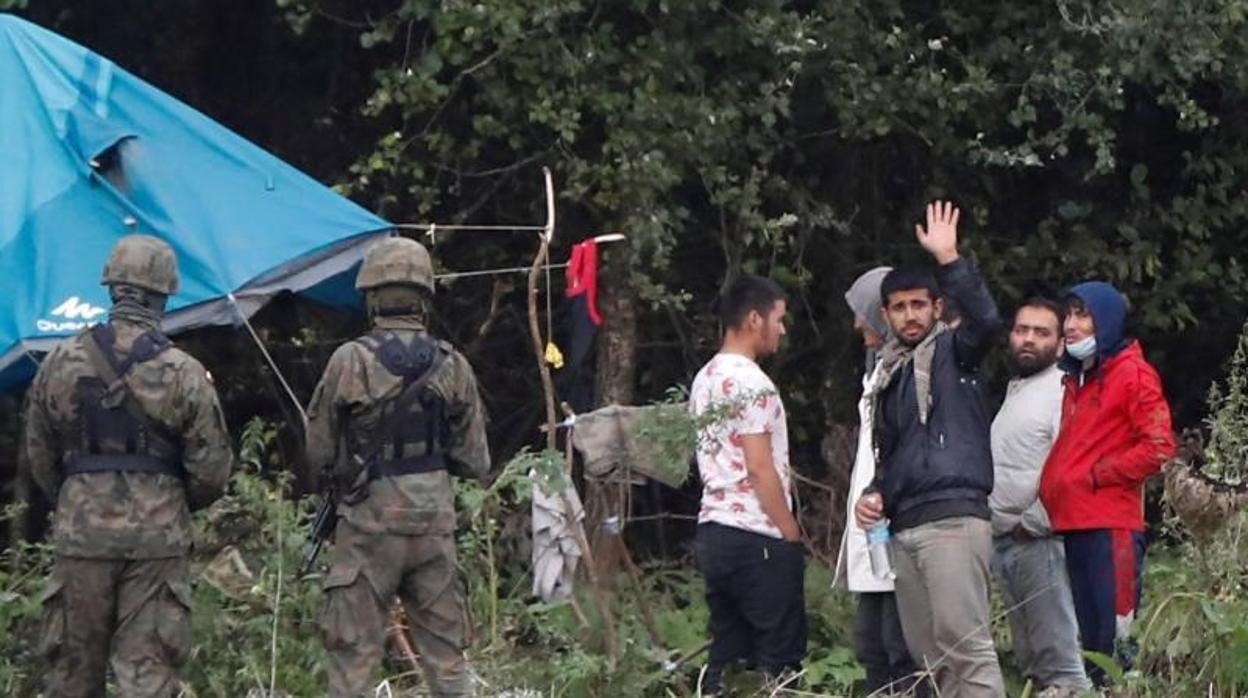 La guardia fronteriza polaca junto a un grupo de migrantes en la frontera entre Bielorrusia y Polonia