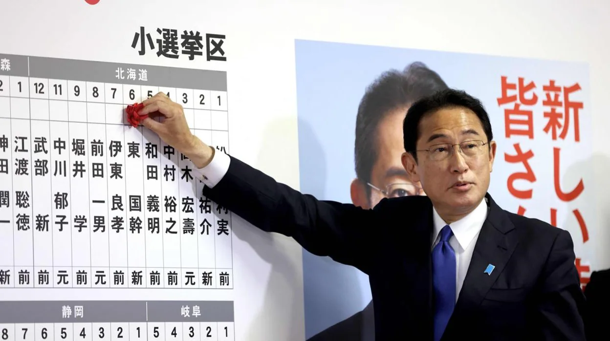 El primer ministro de Japón y líder del gobernante Partido Liberal Democrático, Fumio Kishida, hace gestos mientras coloca rosetas con los nombres de los candidatos exitosos