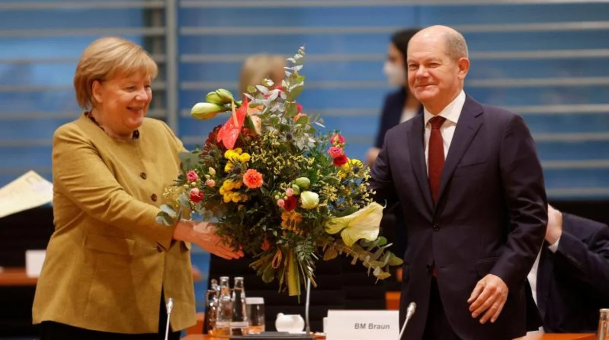 La canciller alemana en funciones, Angela Merkel, recibe un ramo de flores de su ministro de Finanzas y próximo sucesor, el socialdemócrata Olaf Scholz