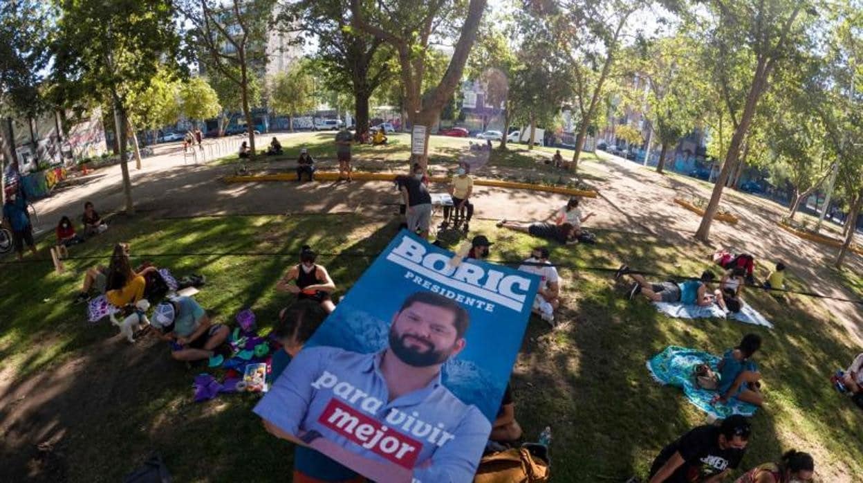 Seguidores de Gabriel Boric se disponen a colgar un cartel electoral en un parque de Santiago