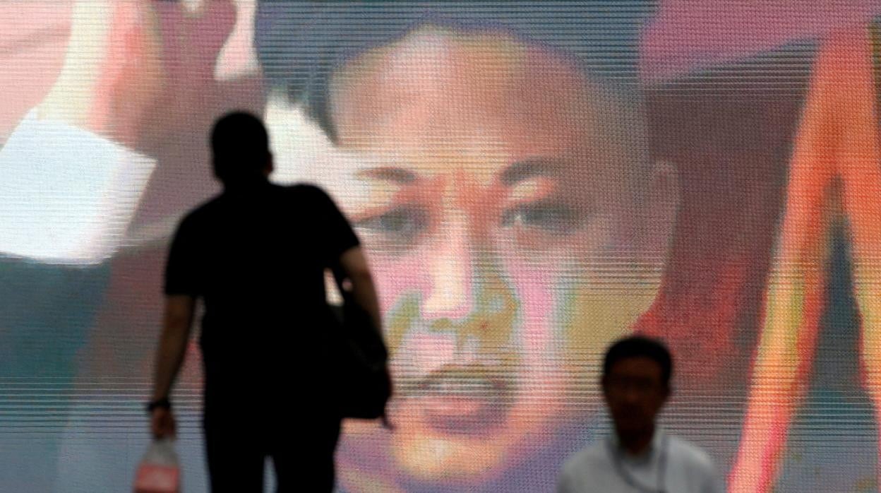 Unos peatones caminan frente a un pantallón que muestra al líder norcoreano