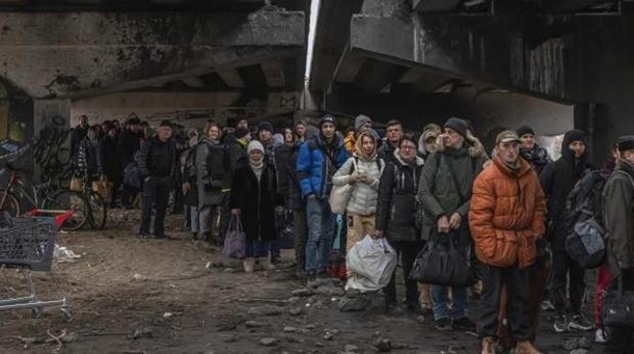 Ciudadanos ucranianos esperan bajo un puente destruido en Irpin