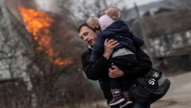 Un padre huye de la guerra con su hija en brazos después de que los rusos atacasen la ciudad de Irvin